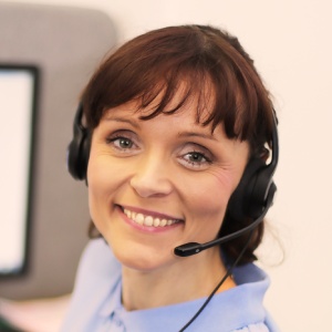 Natural Pharmaceuticals ImuBerin Moteris su laisvų rankų įranga šypsosi klientų aptarnavimo centre.